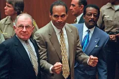 O.J. Simpson w garniturze, z zaciśniętymi pięściami, w sali sądowej w Los Angeles; obok niego obrońcy F. Lee Bailey i Johnnie Cochran, w tle policjanci