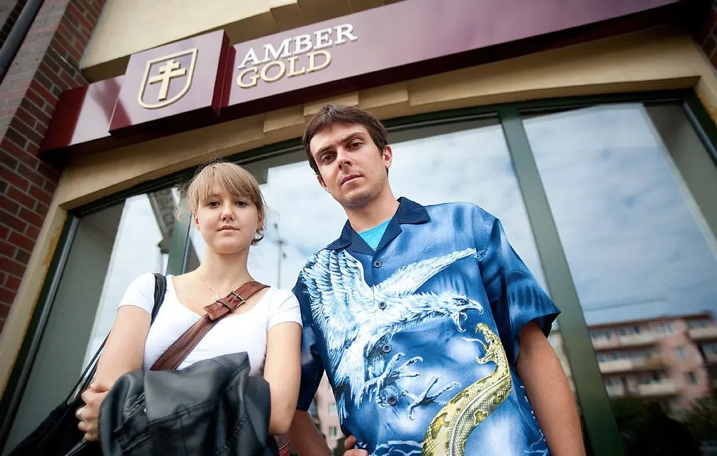 Młoda kobieta i mężczyzna stoją przed placówką z szyldem Amber Gold