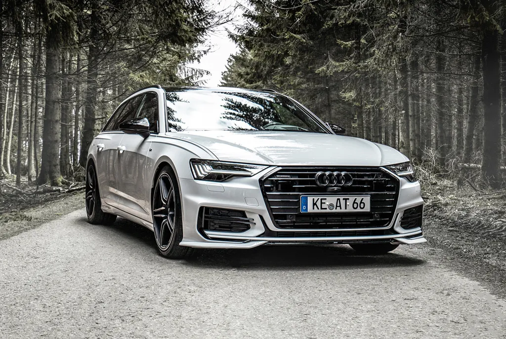 Białe Audi A6 Avant C8 stoi na szutrowej drodze w ciemnym lesie iglastym