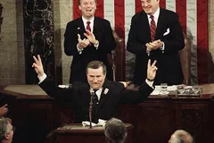 Lech Wałęsa z uniesionymi rękami pokazuje znak zwycięstwa przy mównicy Kongresu USA, za nim na tle amerykańskiej flagi klaszczą wiceprezydent Dan Quayle i spiker Izby Reprezentantów Tom Foley